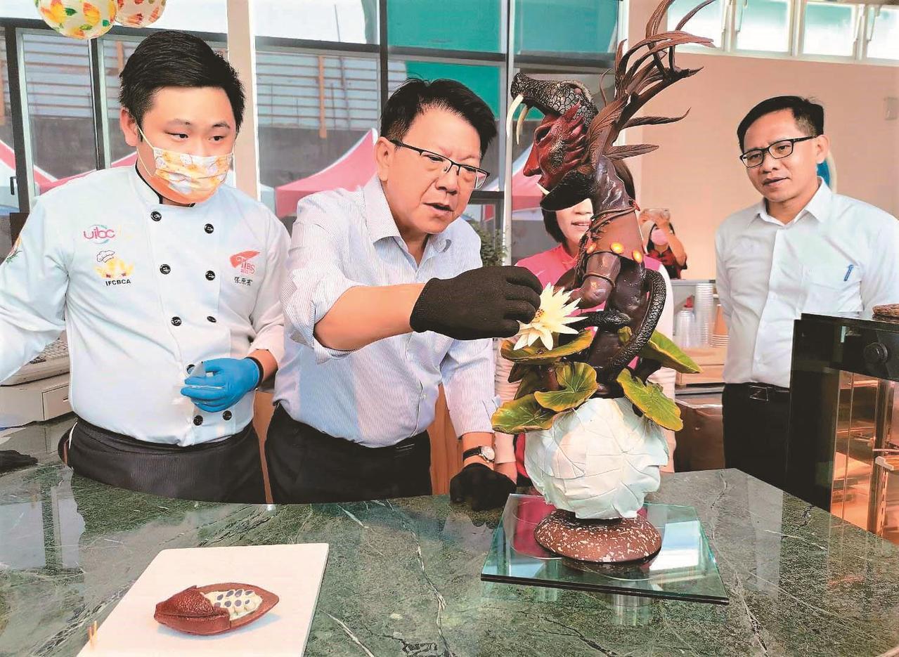 「屏東可可．台灣巧克力節」昨天在萬巒鄉屏東可可園區登場，縣長潘孟安（左二）和巧克力工藝師合製「羽蛇神的祝褔」雕塑。圖／屏東可可園園提供